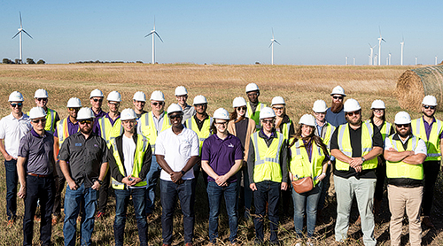 Students in hard hats and vests with windmills