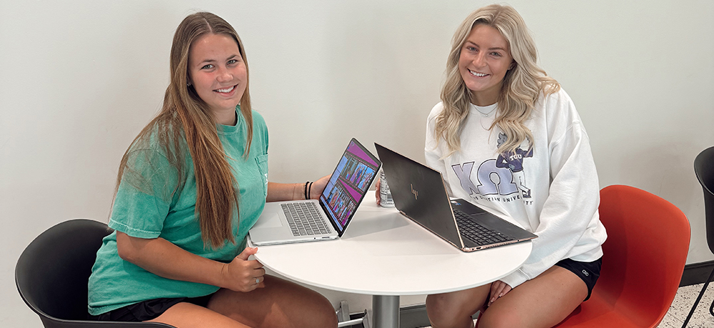 Two girls sitting at a round table with laptops