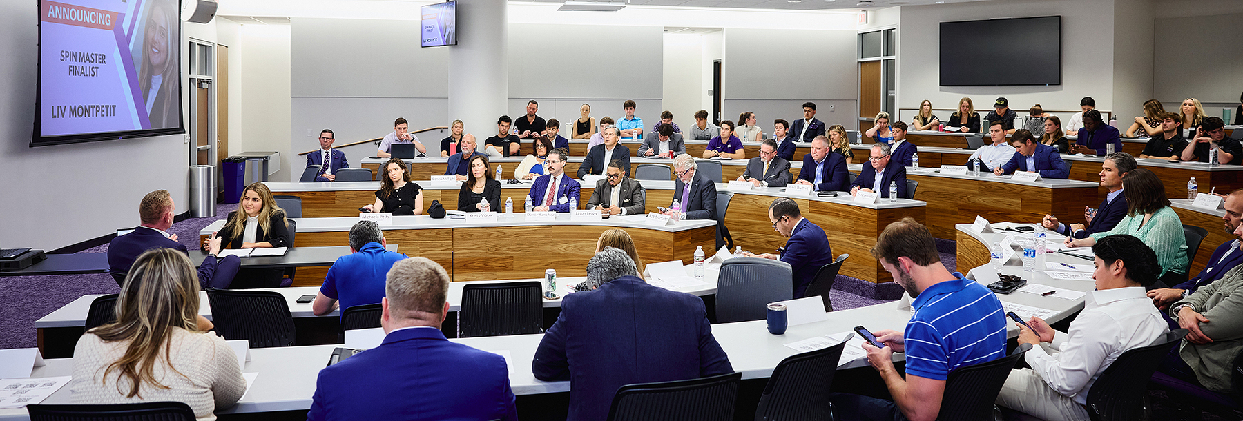 Section Image: Students and judges observe a sales competition 