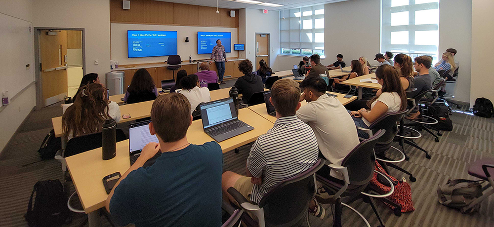 Classroom full of students with professor at the front of the room