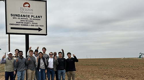 Students in hard hats and vests with windmills