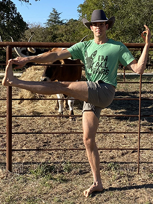 Brendan Hartman doing yoga next to a longhorn