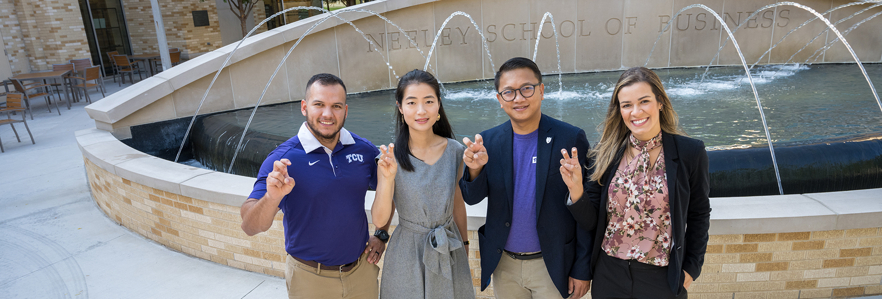 Section Image: Four MBA students with their frogs up at the Neeley Fountain 
